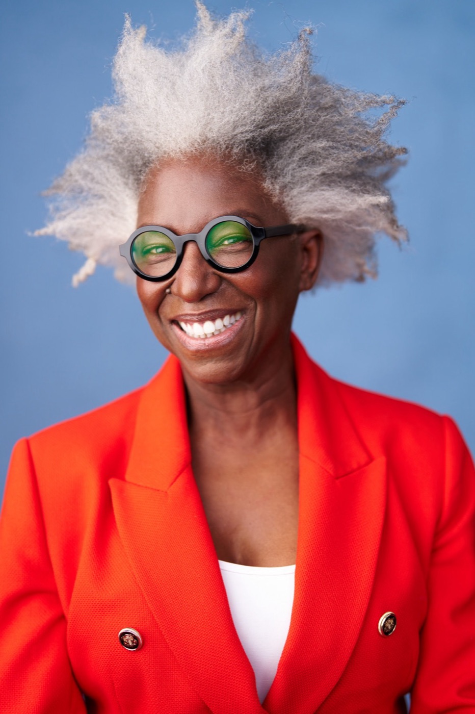 Andrea smiling in a red blazer against a blue background